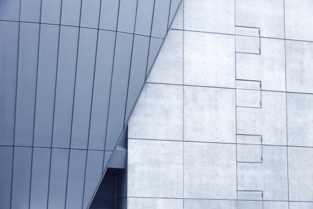 Edificio moderno con ventanales grandes de vidrio esmerilado en azul alineado a muro de concreto